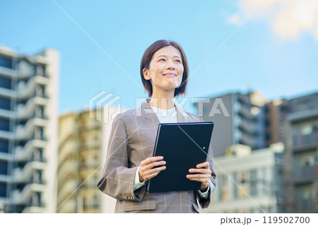 集合住宅の前に立つビジネスウーマン 119502700