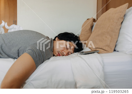 Close up face of sleepy man slept with his mobile phone left near his head. 119503265