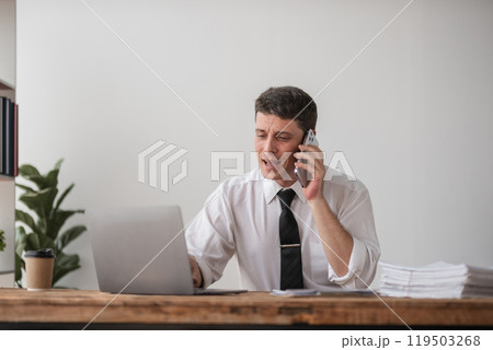Young Businessman Disappointed at Work, Stressful Office Environment, Frustrated Professional on Phone Call, Overwhelmed with Tasks, Corporate Stress, Workplace Challenges, Business Struggles 119503268