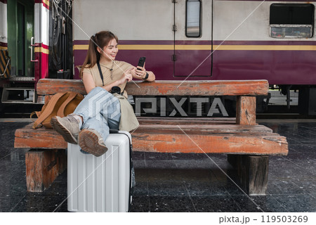 Asian woman waiting at train station, using smartphone, concept of patience Asian woman waiting at train station, using smartphone, concept of patience 119503269