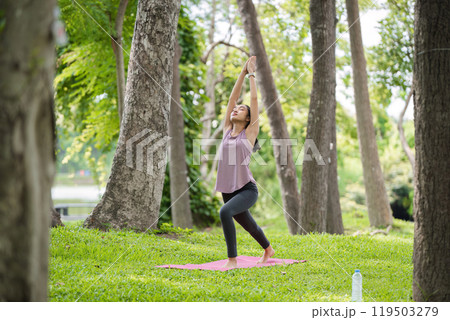 Woman Practicing Yoga in the Park, Relaxing and Meditating Outdoors in a Serene Natural Setting Woman Practicing Yoga in the Park, Relaxing and Meditating Outdoors in a Serene Natural Setting 119503279