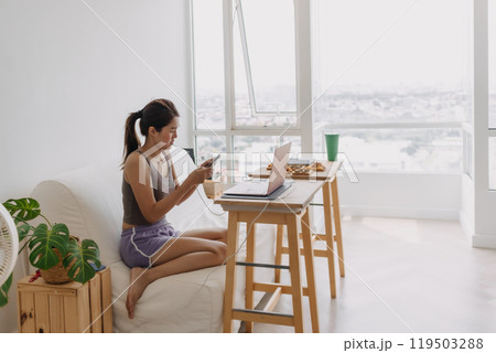 Woman working at home got distracted with the mobile phone. 119503288