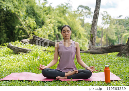 Woman Practicing Yoga Outdoors on a Sunny Day, Meditating on a Pink Mat in a Serene Green Park with Trees in the Background Woman Practicing Yoga Outdoors on a Sunny Day, Meditating on a Pink Mat in a Serene Green Park with Trees in the Background 119503289