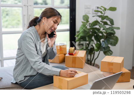 Young Woman Managing Online Sales Business, Taking Orders and Preparing Shipment in a Modern Home Office Young Woman Managing Online Sales Business, Taking Orders and Preparing Shipment in a Modern Home Office 119503298
