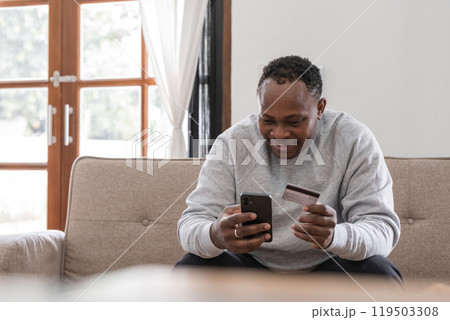 African American man using smartphone and credit card on sofa at home, Concept of mobile banking African American man using smartphone and credit card on sofa at home, Concept of mobile banking 119503308