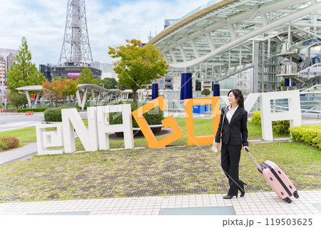 スーツケースを牽いて名古屋に出張する若いビジネスウーマン スーツケースを牽いて名古屋に出張する若いビジネスウーマン 119503625