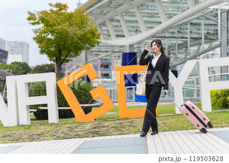 スーツケースを牽いて名古屋に出張する若いビジネスウーマン スーツケースを牽いて名古屋に出張する若いビジネスウーマン 119503628