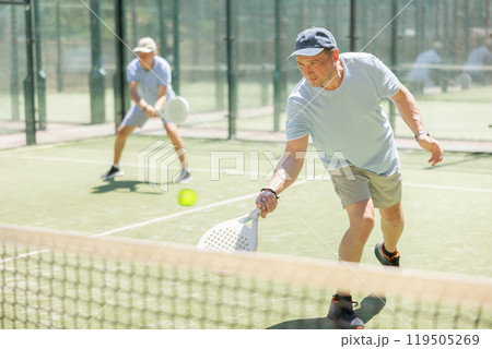 Men play padel on an outdoor tennis court. Hitting the ball with racket Men play padel on an outdoor tennis court. Hitting the ball with racket 119505269