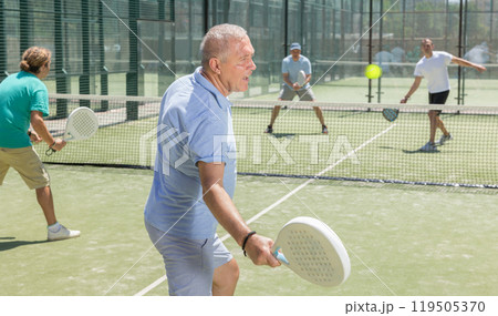 Mature man playing padel game in court on sunny day Mature man playing padel game in court on sunny day 119505370