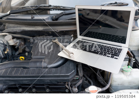 Laptop computer and wrench tool placing inside car's hood on car engine. Laptop computer and wrench tool placing inside car's hood on car engine. 119505384
