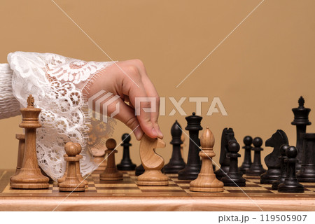 Hand in lace blouse moving chess piece on board. Hand in lace blouse moving chess piece on board. 119505907