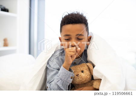 Young African boy in bed with teddy bear coughing Young African boy in bed with teddy bear coughing 119506661