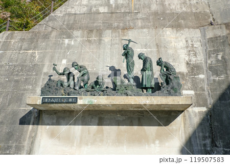Kurobe Dam, Tateyama, Toyama, Chubu, Japan A bronze sculpture depicting laborers engaged in various activities, mounted on a concrete wall. 119507583