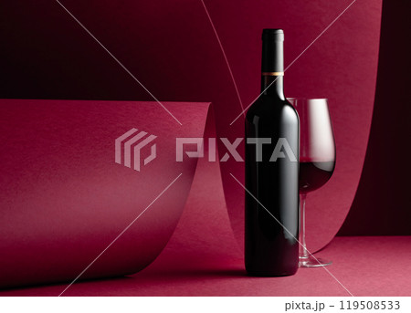 Bottle and glass of red wine on a red paper background. Bottle and glass of red wine on a red paper background. 119508533