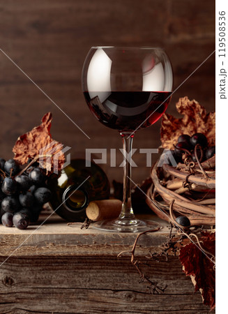 Glass and bottle of red wine on an old wooden table. Glass and bottle of red wine on an old wooden table. 119508536
