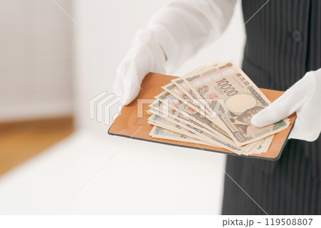 お金を渡す白い手袋の女性 119508807