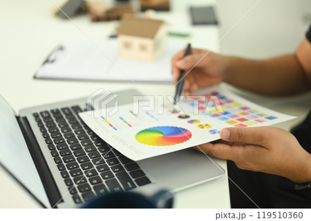 An interior designer reviewing a color chart while working on new design project at a desk An interior designer reviewing a color chart while working on new design project at a desk 119510360
