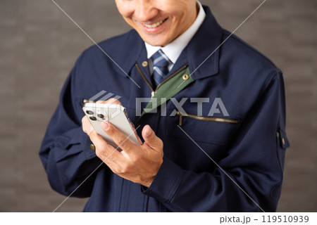 スマホを見ながら笑う作業着を着たミドル男性ビジネスマン 119510939