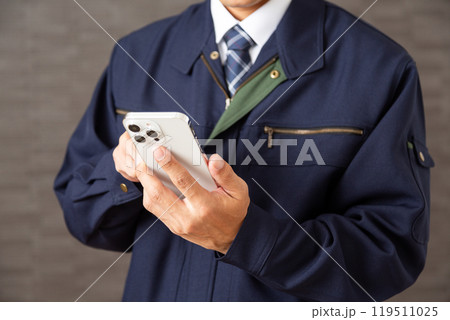 スマホを操作する作業着を着たミドル男性ビジネスマン スマホを操作する作業着を着たミドル男性ビジネスマン 119511025