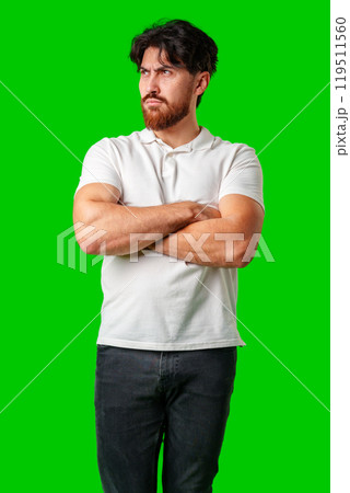 A man with a serious expression stands with crossed arms against a vibrant green background 119511560