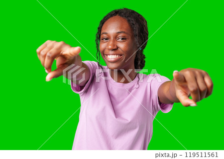 A young woman playfully pointing with a smile against a bright green background A young woman playfully pointing with a smile against a bright green background 119511561