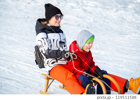 Young adult mother with cute baby boy son enjoy have fun sledging downhilll at frozen white snow hill woods forest park landscape bright sunny cold winter day. Outdoors winter season family activity 119511586