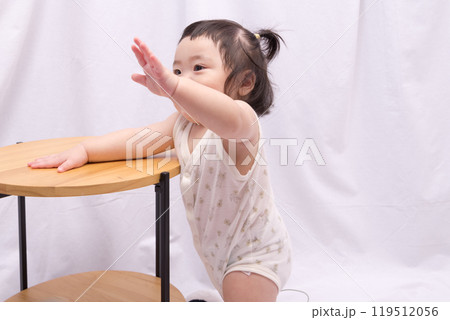 【テーブルでつかまり立ちをするツインテールの赤ちゃん】 【テーブルでつかまり立ちをするツインテールの赤ちゃん】 119512056