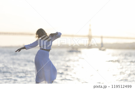 Woman dancing on the beach at sunset with golden gate bridge in background 119512499