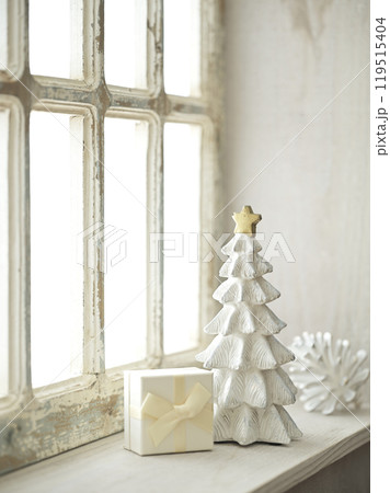 明るい窓辺に置かれたクリスマスツリーとプレゼントボックス 119515404