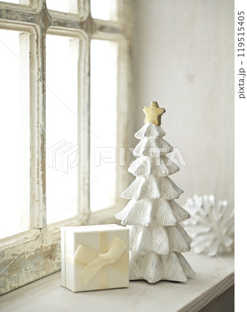 明るい窓辺に置かれたクリスマスツリーとプレゼントボックス 119515405