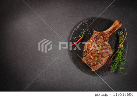 Tomahawk rib beef steak with spices and herbs on a dark background. top view. copy space for text 119515600