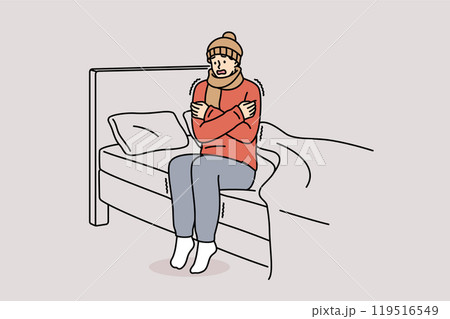 Freezing man is shaking sitting on bed and feeling chills and cold, dressed in hat and scarf 119516549