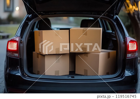 Delivery packages stacked in the trunk of a black car parked outside during early evening hours 119516745