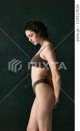 Side profile of young woman, her body in natural pose, emphasizing her quiet confidence and soft texture of her skin. 119517656