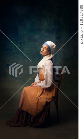 Cinematic portrait of elegant young woman wearing vintage-inspired clothes. Girl with white pearl against dark vintage background. 119517889