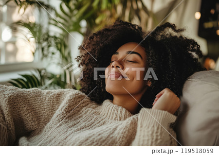 A woman relaxes comfortably in a cozy sweater while enjoying peaceful moments indoors surrounded by 119518059