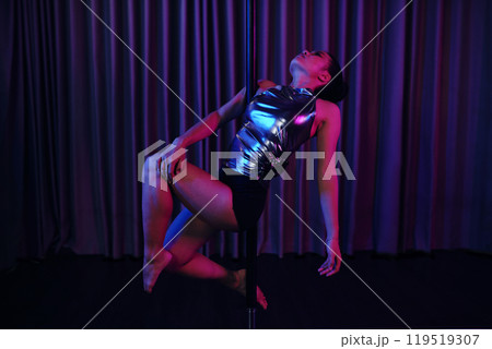 Woman Performing Pole Dance in Shiny Outfit 119519307