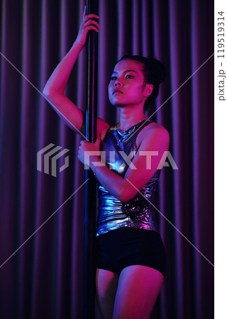 Engaging in Pole Dance Performance with Vibrant Lighting 119519314