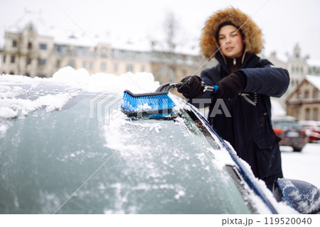 Young man cleaning snow from car with brush. Transport, winter, weather, people and vehicle concept. Young man cleaning snow from car with brush. Transport, winter, weather, people and vehicle concept. 119520040