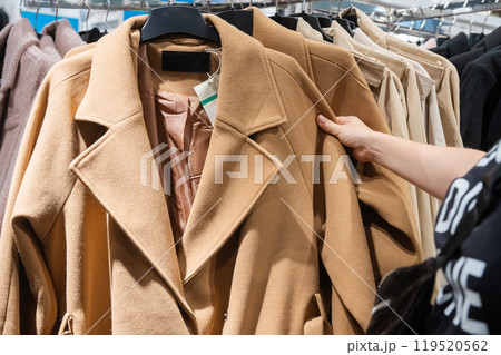 Customer Hand Picking Coat from Clothing Rack in Store 119520562