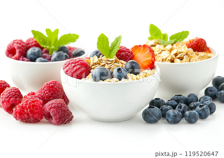 Delicious bowls of yogurt topped with fresh berries and granola served on a clean, white background 119520647