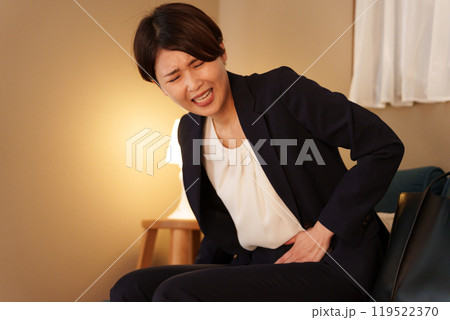 夜に腹痛になる女性ビジネスマン（生理痛・スーツ） 119522370