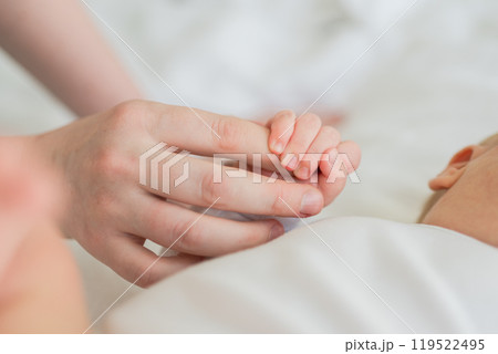Happy family. Tiny newborn infant baby little hand on mother hand palm. Newborn baby holding parent finger after birth. Mom baby at home. Support protection of new life. Handle with care Happy family. Tiny newborn infant baby little hand on mother hand palm. Newborn baby holding parent finger after birth. Mom baby at home. Support protection of new life. Handle with care 119522495