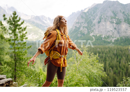 Happy woman with a yellow hiking backpack enjoying the mountain landscape. Travel concept. Happy woman with a yellow hiking backpack enjoying the mountain landscape. Travel concept. 119523557
