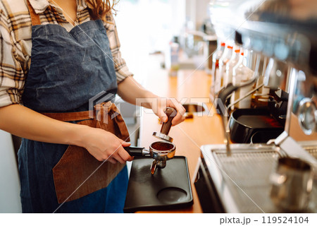 Woman bartender prepares a drink using a coffee machine in a cafe. Takeaway food. Woman bartender prepares a drink using a coffee machine in a cafe. Takeaway food. 119524104