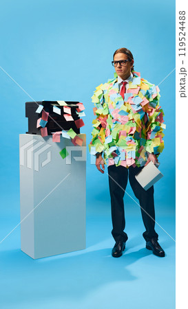 Businessman overloaded with office tasks. Man in formal wear and glasses standing with book, fully covered with sticky notes 119524488