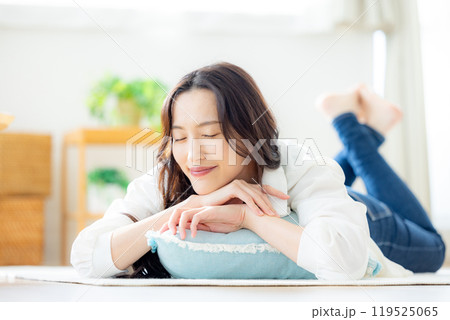 リビングで寝転ぶ笑顔の若い女性 リビングで寝転ぶ笑顔の若い女性 119525065