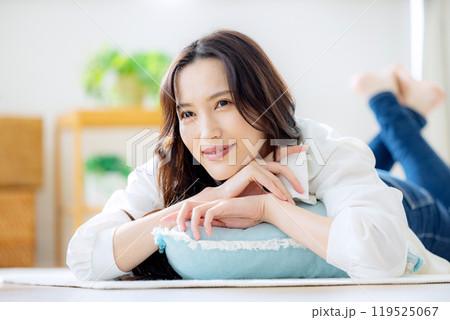 リビングで寝転ぶ笑顔の若い女性 リビングで寝転ぶ笑顔の若い女性 119525067