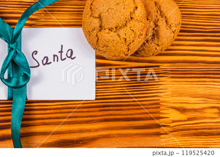 note to santa with green ribbon on wooden board and cookies, christmas concept 119525420