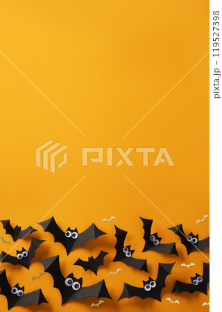 Halloween background with black paper bats and google eyes on an orange backdrop. Place for your text, invitation, advert. 119527398